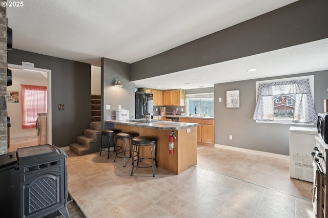 kitchen featuring black refrigerator, washer / clothes dryer, sink, a breakfast bar area, and kitchen peninsula