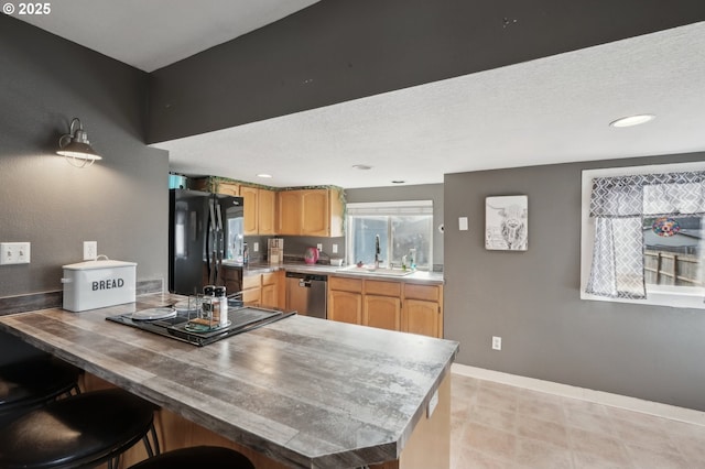 kitchen featuring sink, stainless steel dishwasher, kitchen peninsula, and black fridge