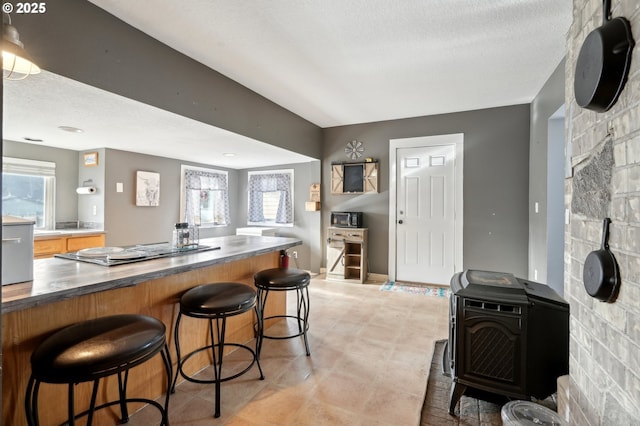 kitchen with stainless steel gas cooktop, a textured ceiling, and a kitchen bar