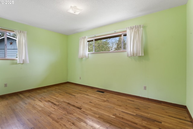 empty room featuring hardwood / wood-style flooring, baseboards, and a textured ceiling