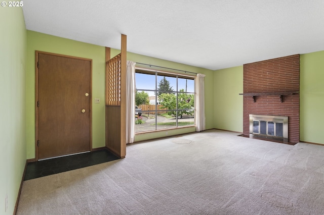 unfurnished living room with carpet floors, a fireplace, baseboards, and a textured ceiling