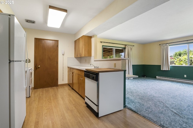 kitchen with white appliances, a sink, a baseboard heating unit, and light wood-style floors