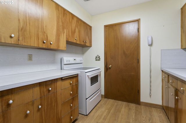 kitchen with electric range, light wood-style floors, light countertops, and brown cabinetry