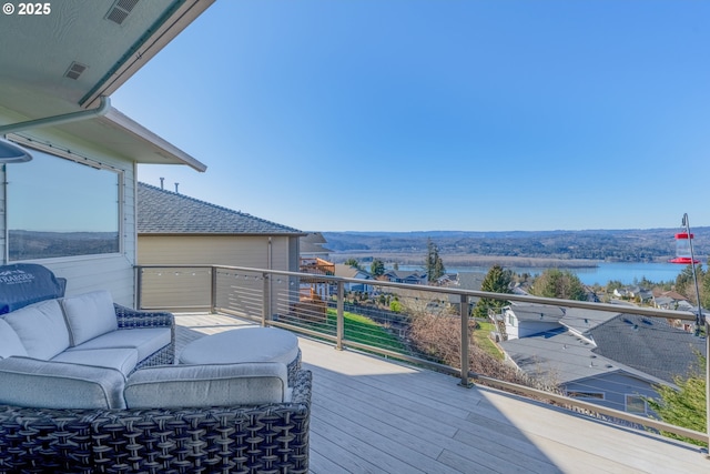 wooden deck featuring visible vents, a water view, and an outdoor living space