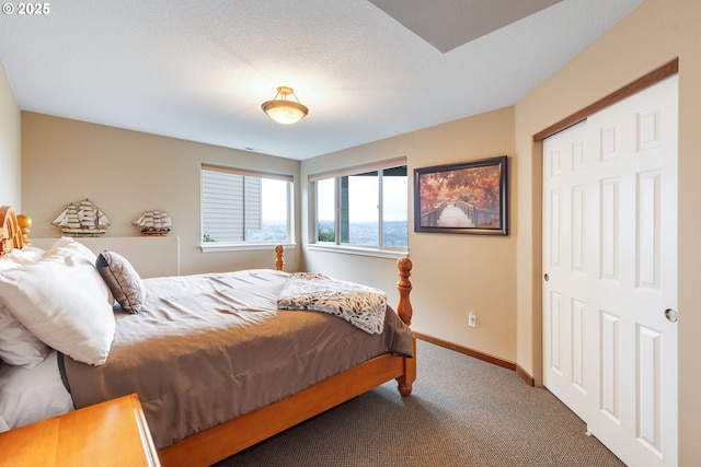 bedroom featuring a textured ceiling, a closet, baseboards, and carpet flooring