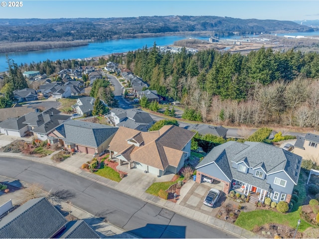 drone / aerial view with a water view, a wooded view, and a residential view