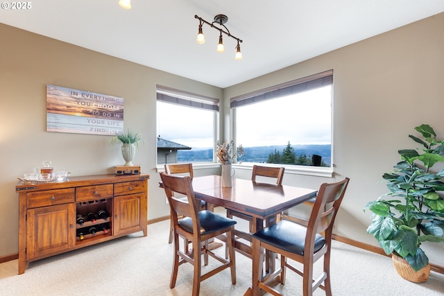 dining area with baseboards and light colored carpet