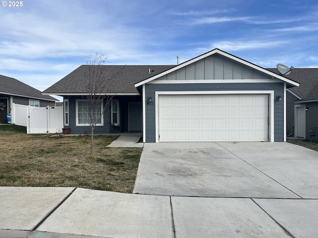 ranch-style house featuring a front lawn, an attached garage, driveway, and fence