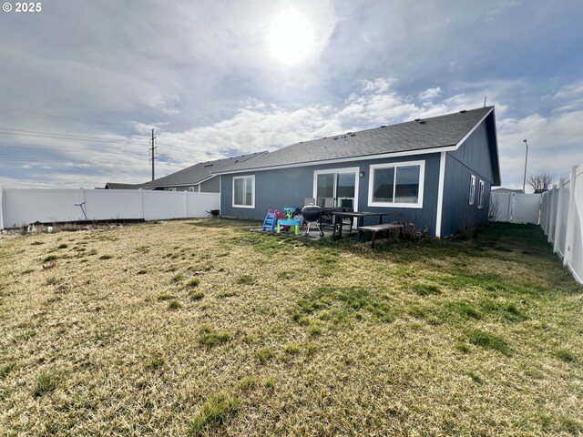 rear view of house with a yard and a fenced backyard