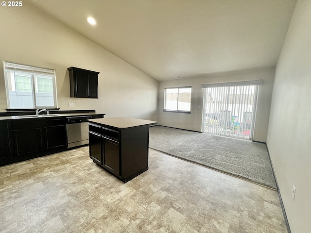 kitchen featuring light carpet, a sink, stainless steel dishwasher, lofted ceiling, and dark cabinets