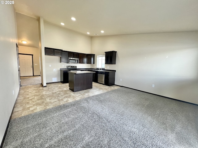 kitchen with high vaulted ceiling, a kitchen island, recessed lighting, stainless steel appliances, and open floor plan