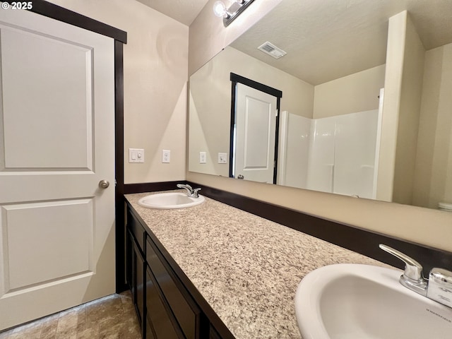 bathroom with double vanity, visible vents, and a sink