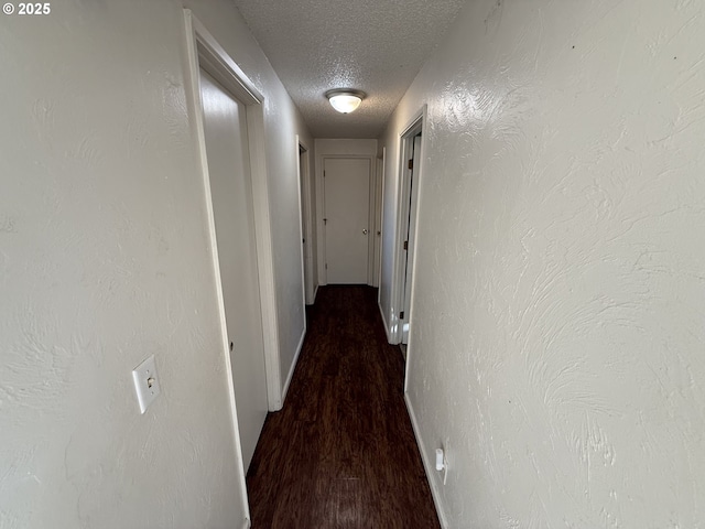 corridor with dark wood-type flooring and a textured ceiling