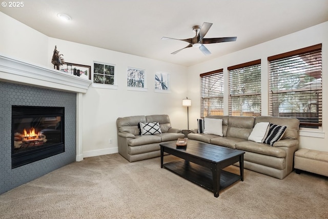 living room featuring a glass covered fireplace, light colored carpet, baseboards, and a ceiling fan