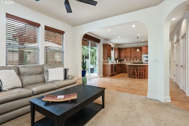 living room with recessed lighting, arched walkways, light tile patterned floors, baseboards, and ceiling fan