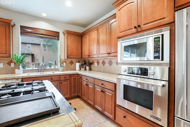 kitchen with backsplash, recessed lighting, light tile patterned flooring, stainless steel appliances, and a sink