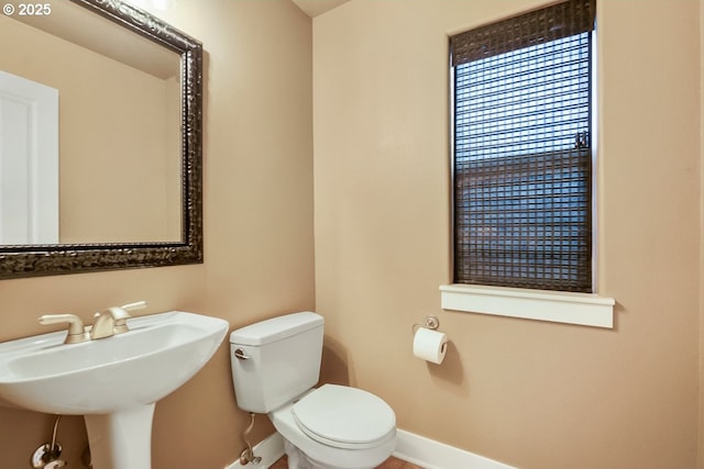 half bathroom featuring toilet and baseboards