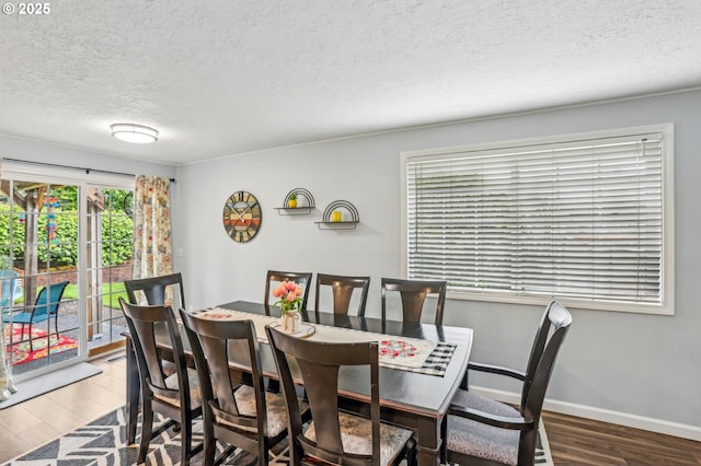 dining room with a textured ceiling, wood finished floors, and baseboards