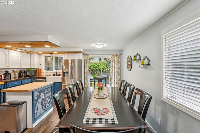 dining area with a textured ceiling and dark wood-type flooring