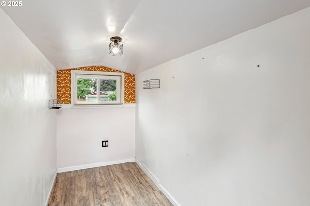 unfurnished room with light wood-style floors, vaulted ceiling, and baseboards