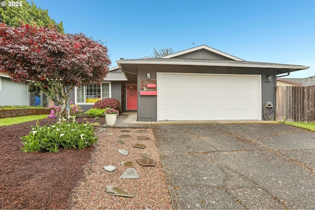 single story home featuring concrete driveway, a garage, and fence