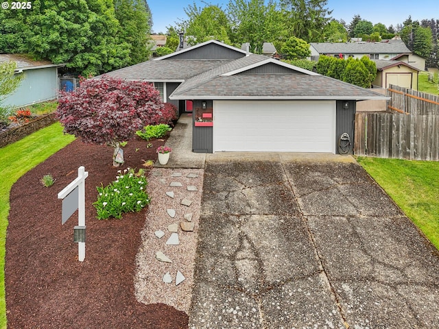 view of front of property with fence, roof with shingles, a garage, and concrete driveway