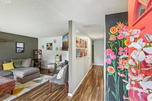 living area featuring wood finished floors, a textured ceiling, and baseboards