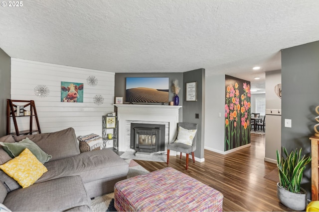 living area with wood finished floors, a fireplace with flush hearth, a textured ceiling, and baseboards
