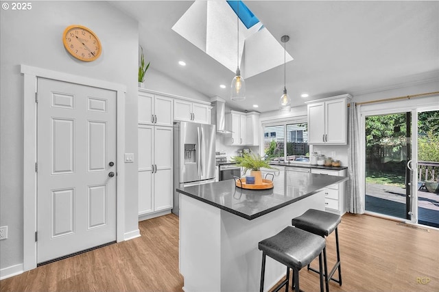 18365 SW Springfield St, Beaverton, OR 97078 - kitchen with stainless steel appliances, wall chimney range hood, a kitchen breakfast bar, white cabinets, and dark countertops