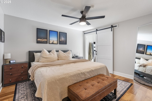 13527 SW Ashbury Ln, Portland, OR 97223 - bedroom with a barn door, light wood-type flooring, and ceiling fan