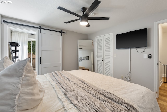 13527 SW Ashbury Ln, Portland, OR 97223 - bedroom with a barn door, light wood-type flooring, a closet, and a ceiling fan