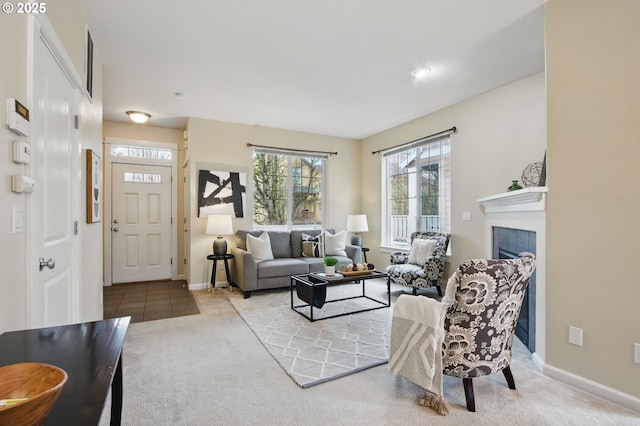 carpeted living area with a tile fireplace and baseboards