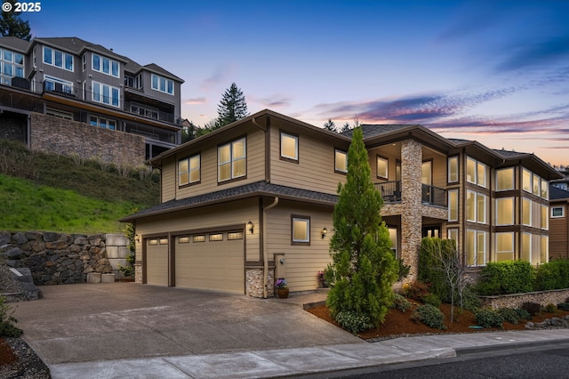 4018 NW Riggs Dr, Portland, OR 97229 - view of front of property with a garage, roof with shingles, stone siding, a balcony, and driveway