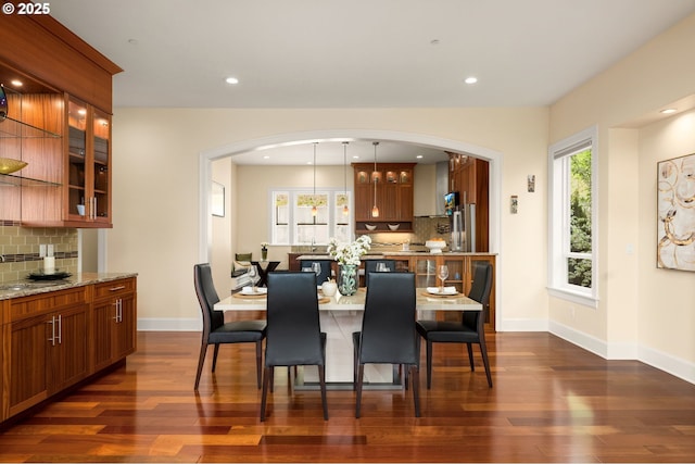 4018 NW Riggs Dr, Portland, OR 97229 - dining area featuring arched walkways, baseboards, dark wood finished floors, and recessed lighting