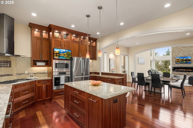4018 NW Riggs Dr, Portland, OR 97229 - kitchen with wall chimney exhaust hood, dark wood-style flooring, brown cabinets, stainless steel appliances, and decorative backsplash