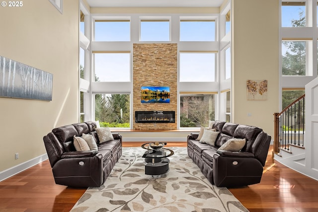 4018 NW Riggs Dr, Portland, OR 97229 - living room featuring a glass covered fireplace, baseboards, a high ceiling, stairs, and hardwood / wood-style floors