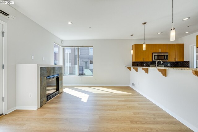8522 N Central St Unit 17-1, Portland, OR 97203 - kitchen with stainless steel microwave, brown cabinets, a kitchen bar, recessed lighting, and a fireplace
