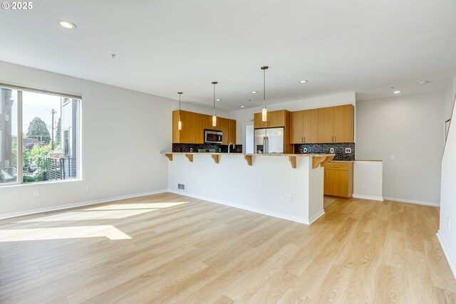 8522 N Central St Unit 17-1, Portland, OR 97203 - kitchen featuring stainless steel appliances, a kitchen breakfast bar, recessed lighting, backsplash, and brown cabinets