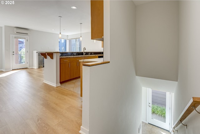 8522 N Central St Unit 17-1, Portland, OR 97203 - kitchen with a wall mounted AC, brown cabinetry, a peninsula, recessed lighting, and pendant lighting
