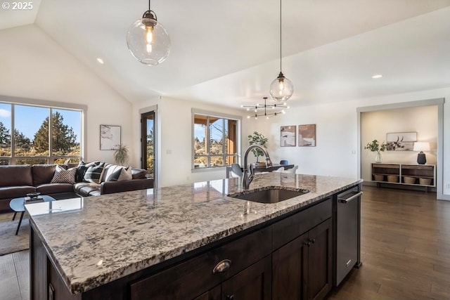 kitchen with sink, a kitchen island with sink, light stone counters, decorative light fixtures, and stainless steel dishwasher