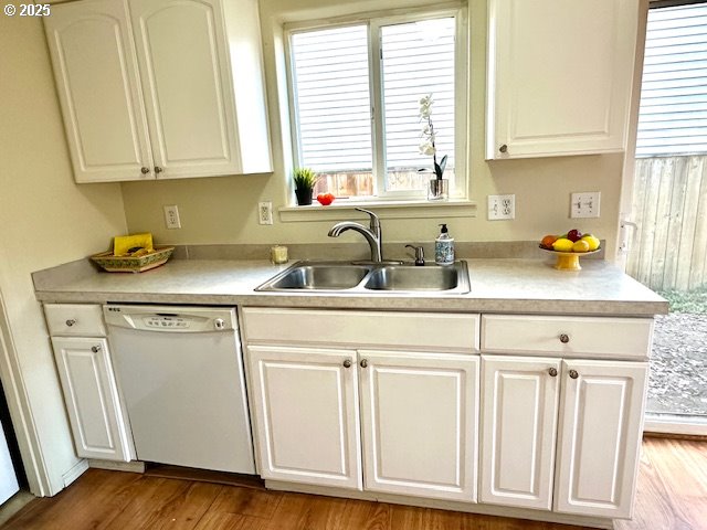 kitchen with white cabinetry, sink, white dishwasher, and light wood-type flooring