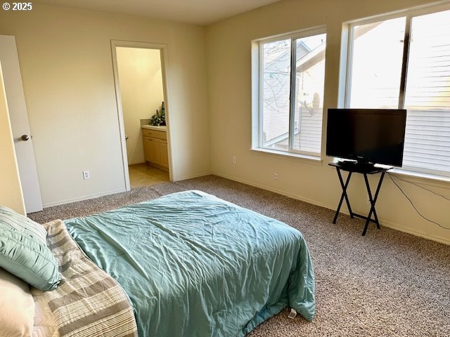 bedroom featuring ensuite bathroom and light carpet