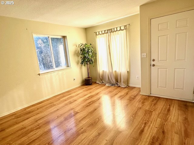 unfurnished room featuring a textured ceiling and light wood-type flooring