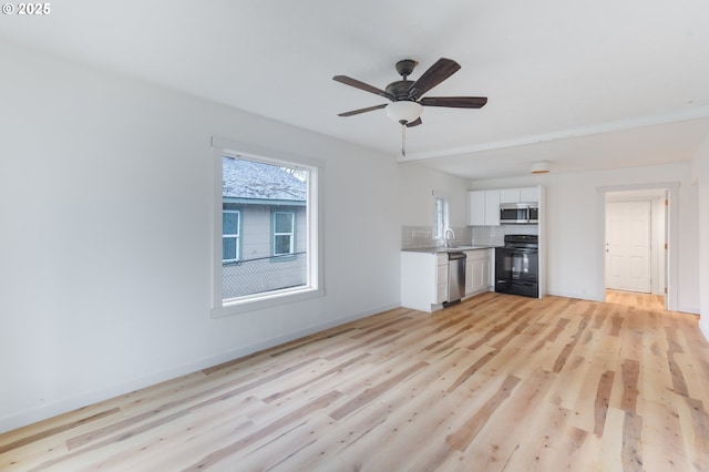 unfurnished living room featuring ceiling fan, light hardwood / wood-style floors, and sink