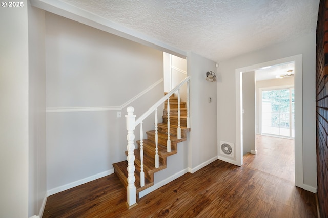 stairs featuring baseboards, a textured ceiling, and wood finished floors