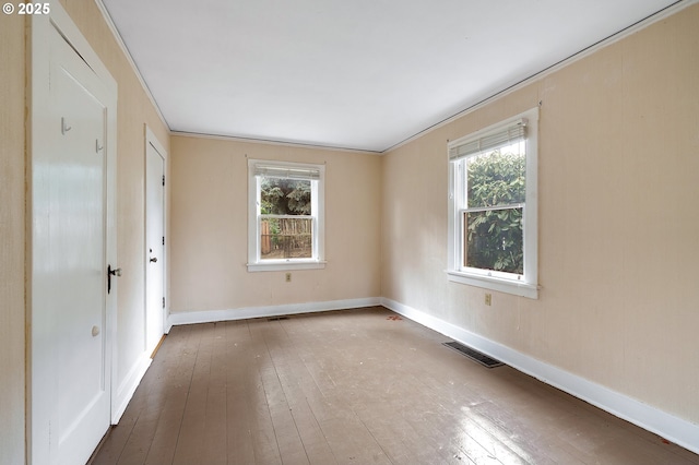 spare room with baseboards, crown molding, visible vents, and wood finished floors