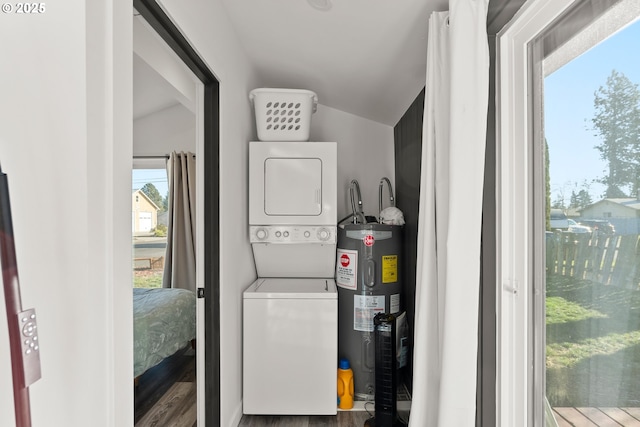 clothes washing area featuring stacked washer and dryer, wood-type flooring, and water heater