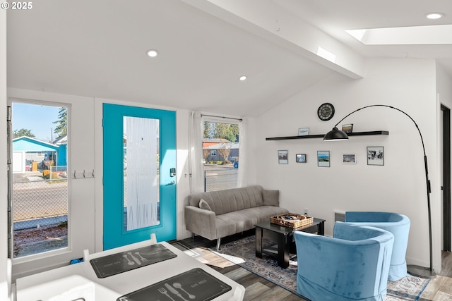 living room with hardwood / wood-style flooring, a wealth of natural light, and vaulted ceiling with skylight