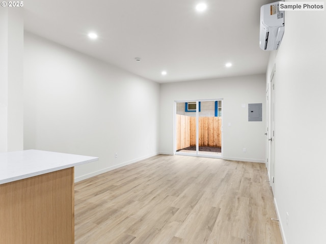 5866 N Missouri Ave Unit 4, Portland, OR 97206 - empty room with electric panel, a wall unit AC, recessed lighting, light wood finished floors, and baseboards