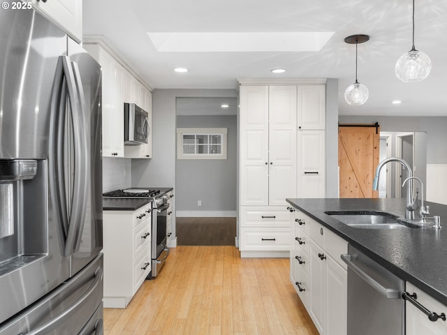 13145 SW 61st Ave, Portland, OR 97219 - kitchen with stainless steel appliances, a skylight, a sink, dark countertops, and recessed lighting